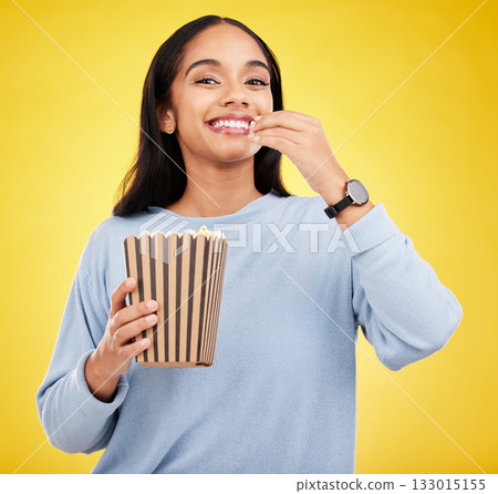 Woman is eating popcorn, happiness and portrait with snack for watching tv or movie on yellow studio background. Streaming service, film and food with corn treat, young female with smile and cinema Woman is eating popcorn, happiness and portrait with snack for watching tv or movie on yellow studio background. Streaming service, film and food with corn treat, young female with smile and cinema 133015155