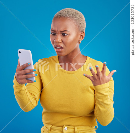 Phone, wtf and confused black woman in studio for fake news, social media and text on blue background. Omg, scam and girl with smartphone notification for phishing alert, glitch or internet problem 133015723