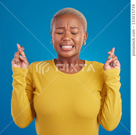 Nervous, fear and fingers crossed by desperate black woman isolated against a studio blue background. Hope, luck and wishing young female doing wish hand gesture worried, miracle and worried Nervous, fear and fingers crossed by desperate black woman isolated against a studio blue background. Hope, luck and wishing young female doing wish hand gesture worried, miracle and worried 133015739