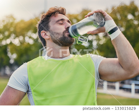 Drinking water, fitness and hydration with a sports man outdoor for a competitive game or event. Exercise, training and health with a male athlete taking a drink from a bottle during a break or rest Drinking water, fitness and hydration with a sports man outdoor for a competitive game or event. Exercise, training and health with a male athlete taking a drink from a bottle during a break or rest 133015829