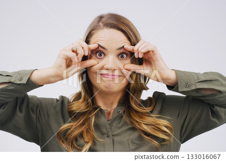Portrait, funny face and eyes with a woman in studio on a gray background looking silly or goofy. Comedy, comic and crazy with a young female person playing or joking indoor for fun or humor Portrait, funny face and eyes with a woman in studio on a gray background looking silly or goofy. Comedy, comic and crazy with a young female person playing or joking indoor for fun or humor 133016067