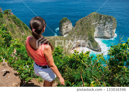 Woman on a cliff and looking on Kelingking beach, Nusa Penida, Indonesia. Woman on a cliff and looking on Kelingking beach, Nusa Penida, Indonesia. 133016396