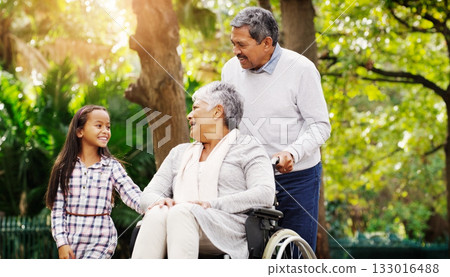 Grandparents, park and a senior woman in a wheelchair together with her husband and granddaughter. Disability, family or kids and a girl child bonding with her senior relatives in a natural garden 133016488