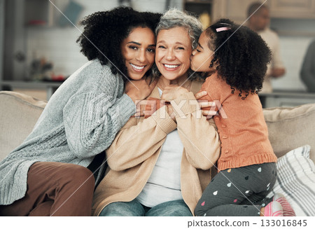 Kiss, portrait and grandmother with girl and woman on a sofa, hug and happy in their home together. Kissing, face and excited senior woman with adult daughter and grandchild on couch, bond and smile 133016845