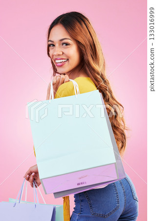 Portrait, shopping and smile with a black woman customer in studio on a pink background for retail. Face, fashion or sale and an attractive young female shopper happy with a deal or promotion Portrait, shopping and smile with a black woman customer in studio on a pink background for retail. Face, fashion or sale and an attractive young female shopper happy with a deal or promotion 133016999