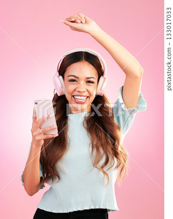 Music headphones, phone and portrait of woman in studio isolated on a pink background. Smile, radio dance and happy female with mobile streaming, enjoying and listening to audio, sound or podcast. 133017033