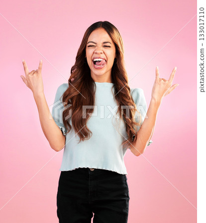 Woman, rock hand gesture and excited wink in studio, heavy metal expression on face and pink background. Crazy, wild hispanic model and hands in devil horn sign with punk attitude and fun happy smile Woman, rock hand gesture and excited wink in studio, heavy metal expression on face and pink background. Crazy, wild hispanic model and hands in devil horn sign with punk attitude and fun happy smile 133017110