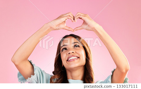 Happy, heart hands and smile with woman in studio for romance, positive and kindness. Love, support and emoji with female and shape isolated on pink background for emotion, hope and gesture 133017111