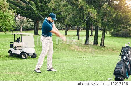 Golf, stroke and hobby with a sports man swinging a club on a field or course for recreation and fun. Golfing, grass and training with a male golfer playing a game on a green during summer 133017198