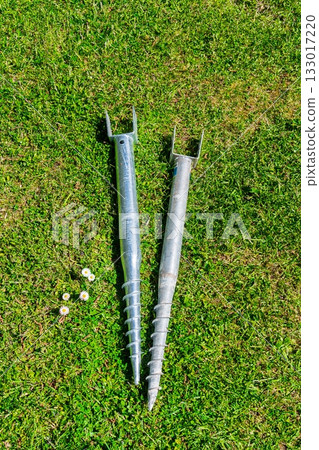 Ground Anchors for Secure Outdoor Structures on Vibrant Green Grass Background, Close-Up Ground Anchors for Secure Outdoor Structures on Vibrant Green Grass Background, Close-Up 133017220