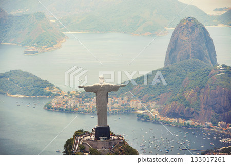 Statue, monument and Christ the Redeemer on mountain for tourism, sightseeing and travel destination. Traveling, Rio de Janeiro and aerial view of symbol, sculpture and city landmark by Brazil ocean 133017261
