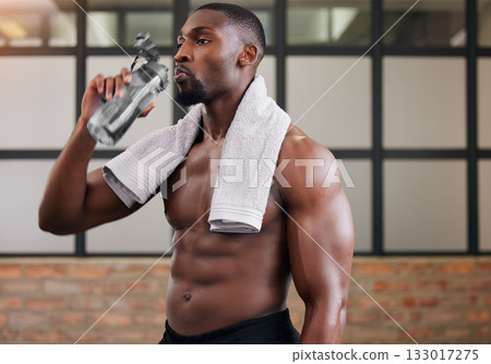 Shirtless bodybuilder, black man and drinking water in gym for health, break and energy of workout, training or diet. Thirsty male, abs and bottle for fitness nutrition, hydration and sports wellness Shirtless bodybuilder, black man and drinking water in gym for health, break and energy of workout, training or diet. Thirsty male, abs and bottle for fitness nutrition, hydration and sports wellness 133017275
