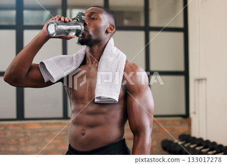 Shirtless black man, gym and water bottle for health, break and energy of workout, training and exercise diet. Thirsty male, abs and drinking for fitness nutrition, body hydration and sports wellness 133017278