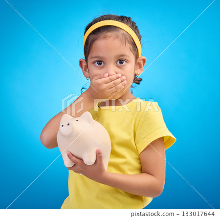 Piggy bank, shocked or surprised child in portrait isolated on blue background savings mistake or investment risk. Wow face of girl kid and saving jar or container for finance or money fear in studio Piggy bank, shocked or surprised child in portrait isolated on blue background savings mistake or investment risk. Wow face of girl kid and saving jar or container for finance or money fear in studio 133017644