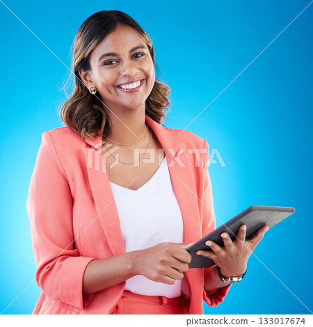 Tablet, smile and portrait of business woman in studio isolated on a blue background. Technology, professional and happy, proud and confident female from India with touch screen for internet browsing 133017674