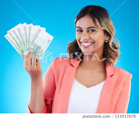 Portrait, smile and business woman with euros in studio isolated on a blue background. Financial winner, face and happy Indian female with cash money after winning lottery, prize and competition. 133017679