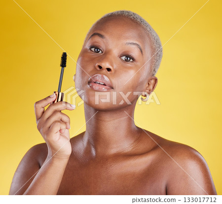Beauty, cosmetics and portrait of black woman with mascara brush in hand in studio isolated on yellow background. Makeup routine, lashes and skincare, face of gen z African model with luxury product. Beauty, cosmetics and portrait of black woman with mascara brush in hand in studio isolated on yellow background. Makeup routine, lashes and skincare, face of gen z African model with luxury product. 133017712