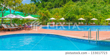 swimming pool at a tropical luxury resort in summer. Tourism and recreation. Landscape panorama with a pool and sun loungers and umbrellas 133017723