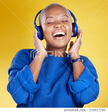 Music, headphones and black woman singing in studio isolated on a yellow background. Podcast, radio singer and happy African female streaming, enjoying and listening to audio, sound track or song. Music, headphones and black woman singing in studio isolated on a yellow background. Podcast, radio singer and happy African female streaming, enjoying and listening to audio, sound track or song. 133017780
