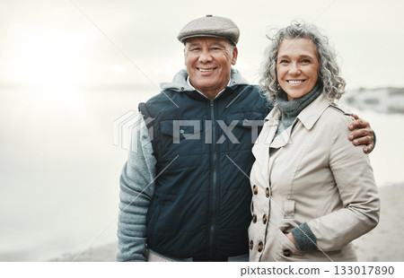 Portrait, winter and senior couple hug, beach for holiday or anniversary getaway with joy, smile or retirement. Face, old woman or mature man embrace, happiness or loving together for romance or love 133017890
