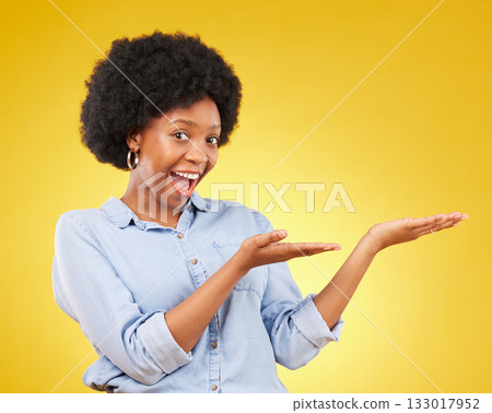 Space, portrait of a black woman in studio showing mockup for advertising or marketing. Happy, smile and face of African female model pointing to mock up for product placement by yellow background. Space, portrait of a black woman in studio showing mockup for advertising or marketing. Happy, smile and face of African female model pointing to mock up for product placement by yellow background. 133017952