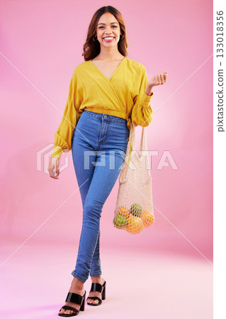 Portrait, shopping and woman nutritionist with fruit in studio for health, diet and healthy living on pink background. Face, groceries and happy girl customer with organic product, nutrition or detox 133018356