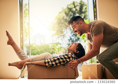 New house, funny and couple pushing box, having fun and bonding in apartment. Real estate, laughing and man and woman in cardboard, play and enjoying quality time together while moving into property. 133018360