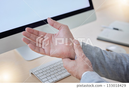 Hand, arthritis and carpal tunnel with a business man in his office, sitting at a desk suffering from joint pain. Stress, medical or anatomy and a male employee struggling with osteoporosis or injury 133018429