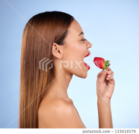 Beauty, wellness and profile of woman with strawberry on blue background for diet, nutrition and healthy eating. Skincare, happy and girl with fruit in studio for cosmetics, makeup and natural snack Beauty, wellness and profile of woman with strawberry on blue background for diet, nutrition and healthy eating. Skincare, happy and girl with fruit in studio for cosmetics, makeup and natural snack 133018579
