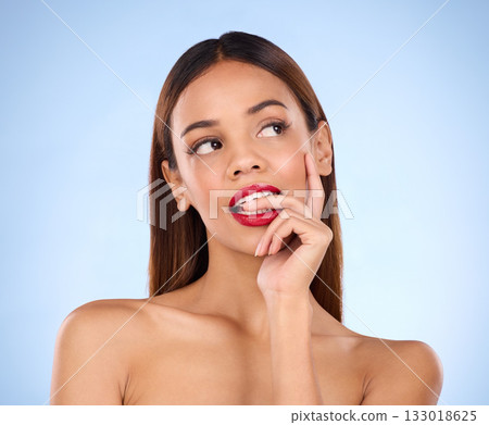 Beauty, face and woman thinking of makeup or cosmetics in studio. Aesthetic female model person on blue background for self care, facial glow and red lipstick with idea for color while biting finger 133018625
