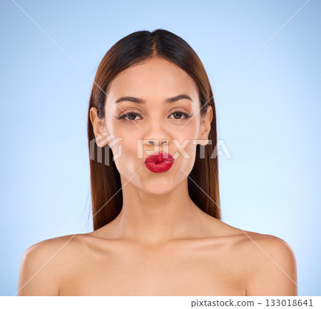 Woman, beauty and red lipstick makeup portrait with cosmetics on face in studio. Aesthetic female model on a blue background for self care, facial glow and shine or color for lips and skin wellness Woman, beauty and red lipstick makeup portrait with cosmetics on face in studio. Aesthetic female model on a blue background for self care, facial glow and shine or color for lips and skin wellness 133018641
