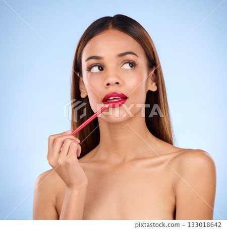 Beauty, woman and red lipliner or lipstick for lips with cosmetics on face in studio. Aesthetic female model thinking on a blue background for self care, facial glow and pencil application for skin Beauty, woman and red lipliner or lipstick for lips with cosmetics on face in studio. Aesthetic female model thinking on a blue background for self care, facial glow and pencil application for skin 133018642