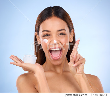 Skincare portrait of excited woman, cream on finger and anti aging skin care on blue background. Cosmetics, facial and face of hispanic model with moisturizer solution or collagen product in studio. Skincare portrait of excited woman, cream on finger and anti aging skin care on blue background. Cosmetics, facial and face of hispanic model with moisturizer solution or collagen product in studio. 133018681