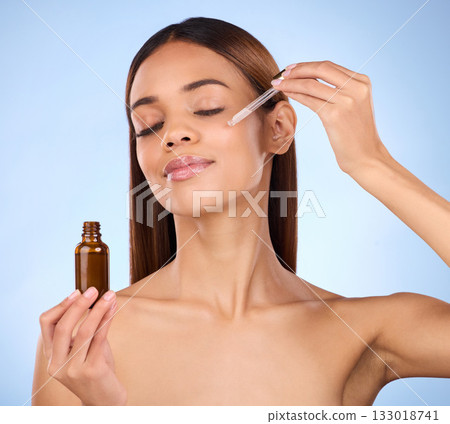 Beauty, skincare and cosmetics, hispanic woman with serum in pipette for anti aging skin glow on blue background. Makeup, facial repair and face of model with solution or collagen product in studio. Beauty, skincare and cosmetics, hispanic woman with serum in pipette for anti aging skin glow on blue background. Makeup, facial repair and face of model with solution or collagen product in studio. 133018741