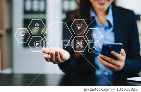 Professional using smartphone with digital holographic dental icons, showcasing innovation, modern healthcare technology, and advanced dentistry solutions Professional using smartphone with digital holographic dental icons, showcasing innovation, modern healthcare technology, and advanced dentistry solutions 133018820