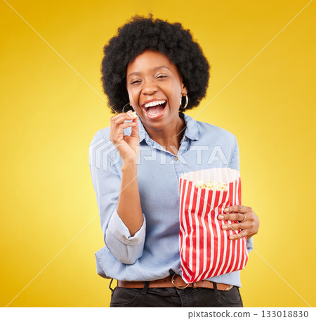 Happy, smile and popcorn with black woman in studio for movie, streaming service and cinema. Laugh, comedy and theatre with female and snack isolated on yellow background for food, tv and film 133018830