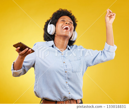 Phone, music headphones and black woman singing in studio isolated on a yellow background. Dance, cellphone and happy female with mobile for streaming, dancing and enjoying radio, podcast or audio. Phone, music headphones and black woman singing in studio isolated on a yellow background. Dance, cellphone and happy female with mobile for streaming, dancing and enjoying radio, podcast or audio. 133018831