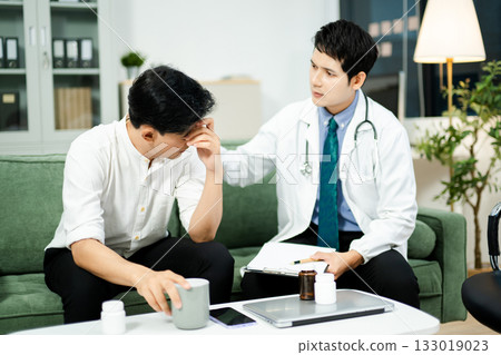 Doctor consulting with a stressed male patient in private clinic. Mental health care, therapy, empathy, and emotional support Doctor consulting with a stressed male patient in private clinic. Mental health care, therapy, empathy, and emotional support 133019023
