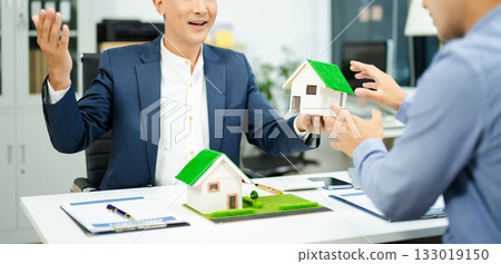 Real estate agent consulting with buyer on house model and pricing using calculator in modern office. and client service. 133019150