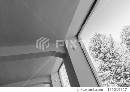 A stark monochrome interior scene featuring angled walls and expansive windows 133019327