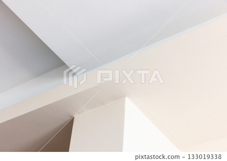 A calm interior scene featuring intersecting white and beige walls with sharp angles A calm interior scene featuring intersecting white and beige walls with sharp angles 133019338