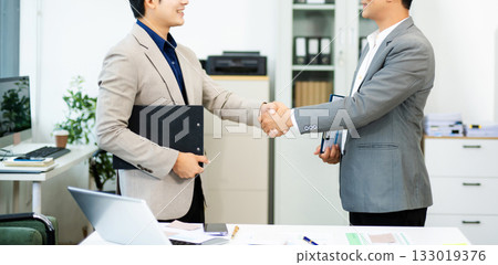 Professional handshake between two businessmen sealing a successful agreement in a modern office Professional handshake between two businessmen sealing a successful agreement in a modern office 133019376