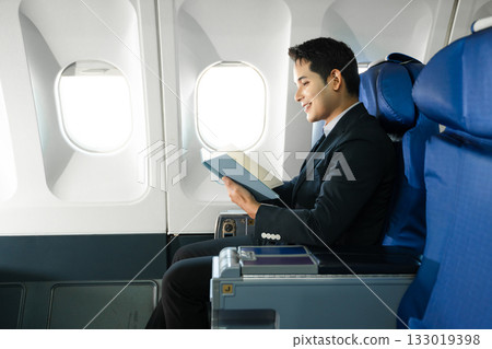 Young Asian executive excels in first class, multitasking with digital tablet, laptop and smartphone. Travel in style, work with grace. 133019398