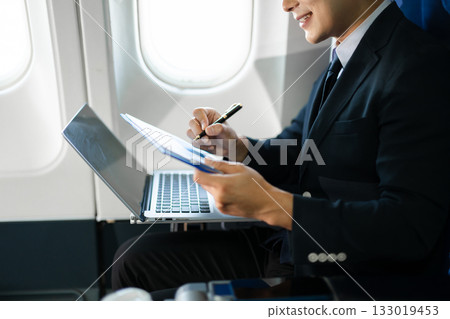 Confident businessman making a phone call in first class, blending luxury air travel with business, technology, and global networking opportunities. 133019453