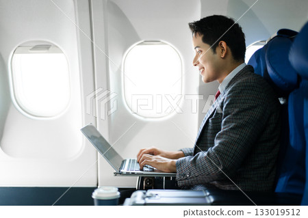 Confident businessman using a laptop in first class, blending productivity, luxury travel, and a modern digital lifestyle for business success. 133019512