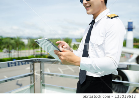 Airline pilot in uniform reviewing checklist outdoors by airplane, perfect for aviation, travel, and professional flight safety themes Airline pilot in uniform reviewing checklist outdoors by airplane, perfect for aviation, travel, and professional flight safety themes 133019618