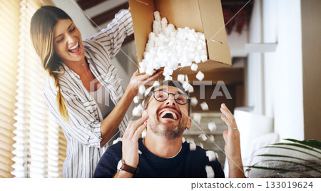 Moving house, property and box with a silly married couple having fun while playing in their new home together. Real estate, comic or comedy with a playful husband and wife joking in the living room 133019624
