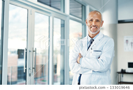 Mature doctor, leadership and portrait with arms crossed in hospital feeling proud from medical work. Healthcare, wellness and professional employee with happiness from health support and job 133019646