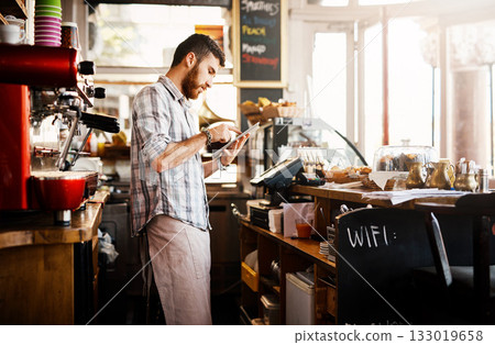 Digital tablet, research and cafe owner working on a startup cafeteria business plan in a restaurant. Technology, entrepreneur and male barista or waiter checking stock on a mobile in his coffee shop Digital tablet, research and cafe owner working on a startup cafeteria business plan in a restaurant. Technology, entrepreneur and male barista or waiter checking stock on a mobile in his coffee shop 133019658