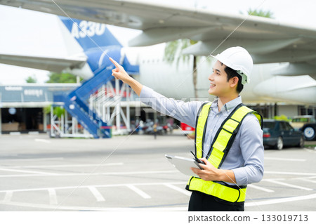 Ground crew engineer in safety vest and hard hat using walkie talkie while checking documents, perfect for aviation, maintenance, Ground crew engineer in safety vest and hard hat using walkie talkie while checking documents, perfect for aviation, maintenance, 133019713